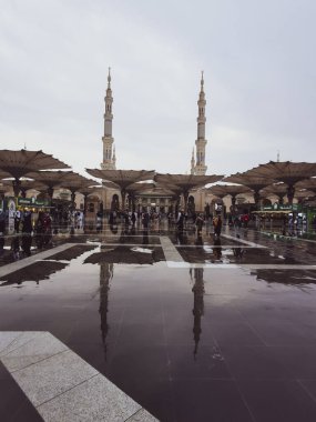 Suudi Arabistan 'ın Medine kentindeki Nabawi camisinin girişinde yürüyen Müslüman hacıların yağmur yansıması. İslam 'ın en kutsal ikinci camii..
