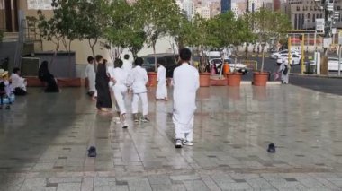 MECCA, KINGDOM of SAUDI ARABIA (KSA) - 12 Haziran 2023: Geleneksel elbise giyen Suudi Arabistan 'lı bir grup genç erkek çocuk, Suudi Arabistan' ın Makkah kentinde kaldırımda futbol oynuyor.