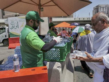 SAUDI ARABIA-JUNE 'NİN MECCA, KINGDOM 4 Haziran 2023: İşçiler Müslüman hacılara soğuk içecek dağıtıyor. Hacc sezonundaki sıcak hava nedeniyle, hacılara susuz kalmamak için bol bol su içmeleri tavsiye edilir..