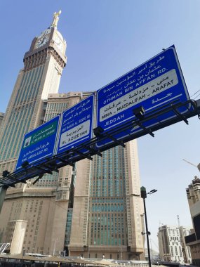 SAUDI ARABIA KINGDOM (KSA) - 8 Haziran 2023: Makkah Saat Kulesi veya Abraj Al Yem Kulesi (solda) ve Suudi Arabistan 'ın Makkah kentindeki büyük şehir trafik işaretleri.