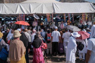 MINA, SAUDI ARABIA 'NIN KINDOM (KSA) -29 Haziran 2023: Mina, Suudi Arabistan' ın bir caddesinde bulunan bir büfeden kimliği belirsiz Asya hacıları yiyecek ve içecek satın aldı.