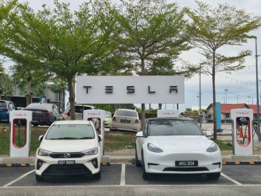 KUANTAN, PAHANG, MALAYSIA - 21 Haziran 2024: İç yanmalı motor (ICE) PERODUA MyVi ve TESLA Model Y Kuantan, Pahang, Malezya 'da şarj olmak üzere belirlenmiş park edilmiş TESLA arabaları.