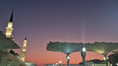 Suudi Arabistan Krallığı Medine 'de sabahın erken saatlerinde dev şemsiyelerin, yeşil kubbenin ve Nabawi camiinin minarelerinin solunda.