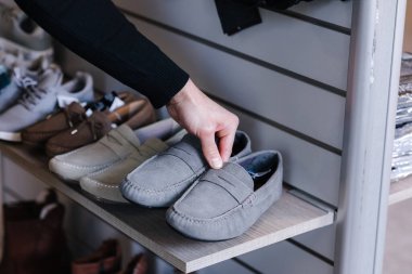 İnsan eli elbise mağazasındaki raftan gri mokasenleri alıyor..