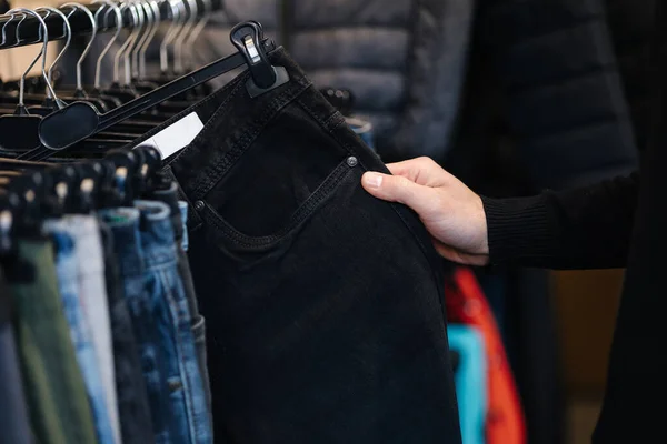 stock image Close up of human hand taking black jeans. Trousers form man.