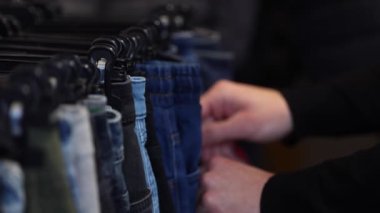 Kıyafet seçen yakışıklı müşterilerin makro videosu. Kotları tutan adamın eli