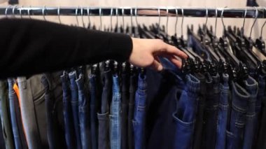 İnsan elini ilk gören kişi hareket eder ve elbise mağazasından kot pantolon seçer. Erkekler için pantolon..