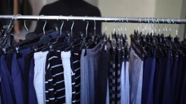 Siyah golfteki yakışıklı müşteri yeni sezon için bir çamaşırcıyı avlamaya çalışıyor. Sonbahar ve kış kıyafetleri rafların önünde duruyordu..
