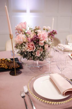 Restorandaki masada dekor unsuru var. Çatal bıçak takımı ve farklı yemekler. Çiçekler..