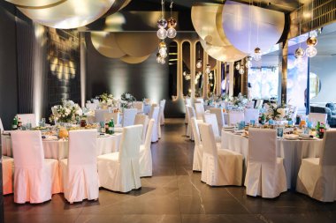 Restoranda lüks dekorasyon. Dekorun farklı unsurlarıyla yuvarlak masa. Güzel çiçekler ve sofra kurulumu.