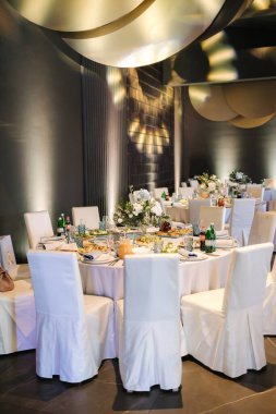 Restoranda lüks dekorasyon. Dekorun farklı unsurlarıyla yuvarlak masa. Güzel çiçekler ve sofra kurulumu.