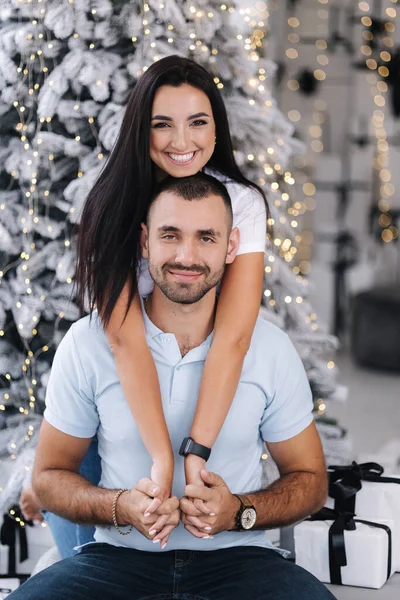 stock image Happy couple of man and woman hug each other and stand in front of fir tree. Attractive female