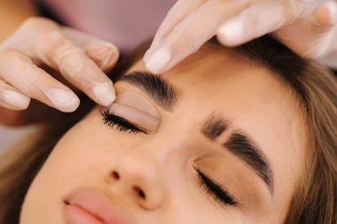 Genç manken için kirpik kaplama prosedürleri yapan bir güzellik uzmanı. Modern kirpik bakım prosedürleri laminasyon ve kirpiklerin genişletilmesi. Profesyonel güzellik salonu.