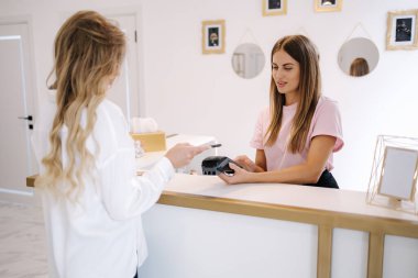 Kadın müşteri, güzellik salonundaki işlemler için ödeme yapıyor..