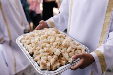 Rahip kardeş, tepsiyi ekmek kübü ile tut. İlk komünyon.