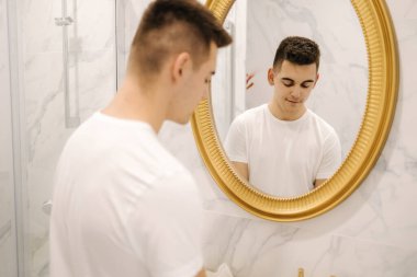 Banyodaki beyaz tişörtlü genç yakışıklı adam.