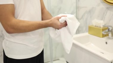 Yakışıklı adam yıkandıktan sonra ellerini siler. Hafif bir banyo. Konsepti temiz tut. Orta el seçimi.