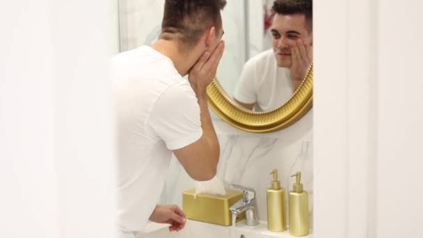 洗顔料でハンサムな男の顔のプロセス 自宅のバスルームシンクで洗顔石鹸 白いTシャツの男性 — ストック動画