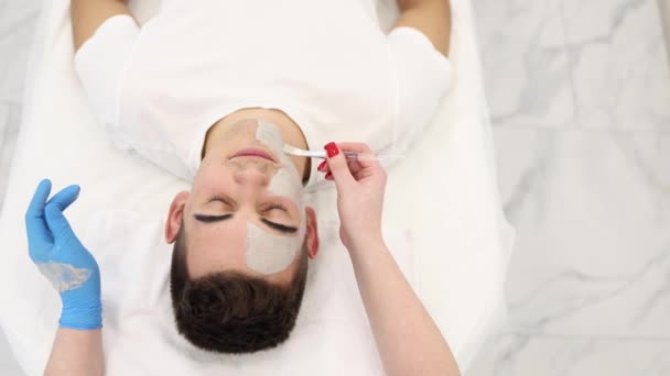 Kosmetolog Nakładający Glinianą Maskę Twarz Mężczyzny Salonie Spa Kosmetyczka Zrobić — Wideo stockowe
