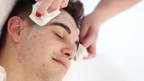 Kosmetolog Zmywa Glinianą Maskę Mokrą Serwetką Twarzy Mężczyzny Salonie Spa — Wideo stockowe