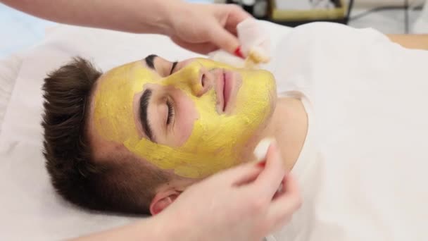 美女工作室里戴着金面具的帅哥的特写镜头 手术期间男性在温泉沙龙 皮肤上的粉刺和黑头粉刺 — 图库视频影像
