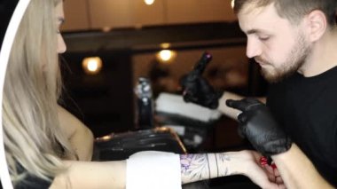 Dövme ustası bir kadının eline dövme yaptırıyor. Kablosuz dövme makinesi, işte güvenlik ve hijyen. Dövme sanatçılarına yakın çekim. Dövme salonu.