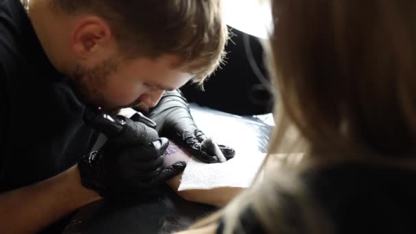 入れ墨のマスターは 女性の手を入れ墨している 職場での無線タトゥーマシン 安全性と衛生 タトゥーアーティストの作品のクローズアップ タトゥーサロン — ストック動画