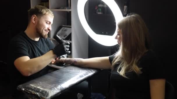 Młody Uśmiechnięty Tatuażysta Tatuuje Kobiecą Dłoń Bezprzewodowa Maszyna Tatuażu Bezpieczeństwo — Wideo stockowe
