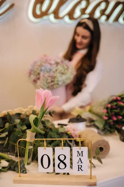 Close-up of woman make spring bouquet. Female florist hold beautiful bouquet of spring flowers in pack paper. Beautiful flower composition of gypsophila.