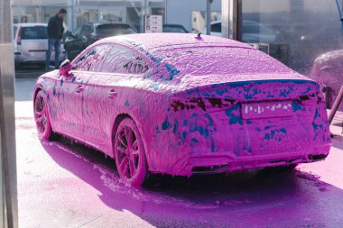 Luxury sport blue car on self servise car washing. Pink foam on auto.