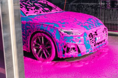 Luxury sport blue car on self servise car washing. Pink foam on auto.