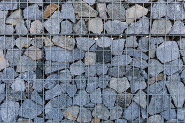 The crushed stone is fixed in the mesh. A fence made of natural stone, crushed stone, granite
