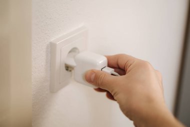 Mans hand puts the charger in the socket. High quality photo