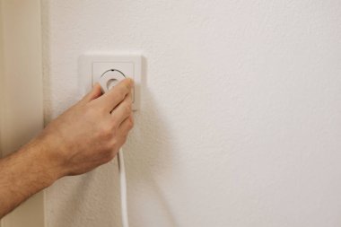 Mans hand puts the charger in the socket. High quality photo