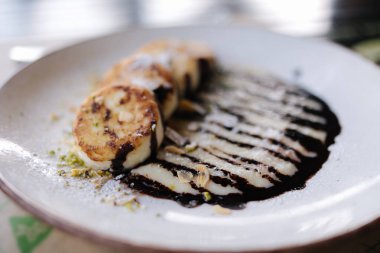 Cheesecakes fried in butter with creamy chocolate cream, grated nuts on top. High quality photo