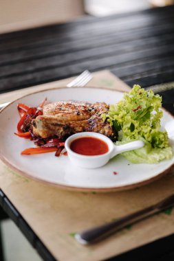 Crispy fried pork on the bone on a pillow of fried sweet onions and sweet bell peppers. sauce and fresh salad. High quality photo