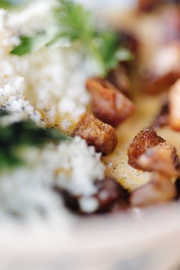 Traditional Ukrainian dish Banosh. Corn porridge in butter sprinkled on fried lard and sheeps cheese. High quality photo