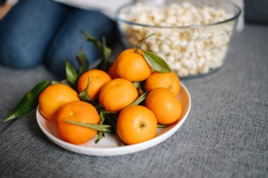 Preparing for watching movie at home. Close-up of tangerines and popcorn. High quality photo