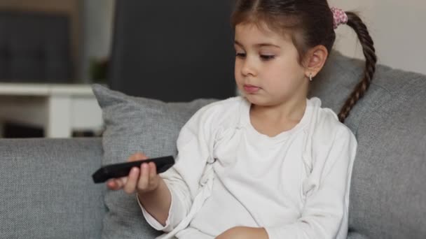 Cute Little Girl Using Remote Controller Watching Cartoons Four Year — Stock videók