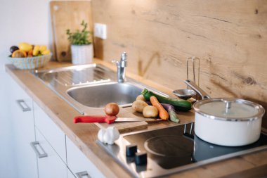 Yemeğin hazırlanacağı mutfağın fotoğrafı, tahta tahtada sebzeler. Beyaz tencere ev yemeği konsepti. Yüksek kalite fotoğraf