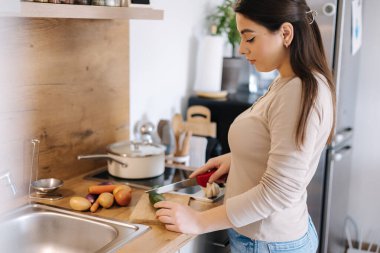 Beautiful young female cutting vegetables on kitchen at home. Home food concept. High quality photo