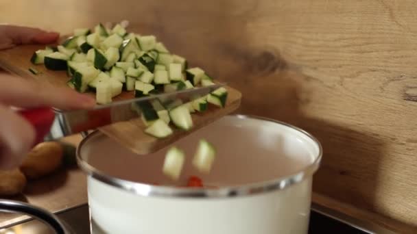 女性は鍋に木製の板からみじん切り玉ねぎを注ぐためにナイフを使用します 高品質4K映像 — ストック動画