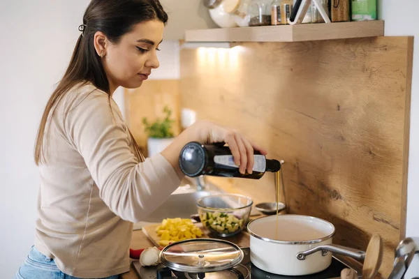 stock image Beautiful woman adds olive oil into saucepan and cooking vegan Mexican food. High quality photo