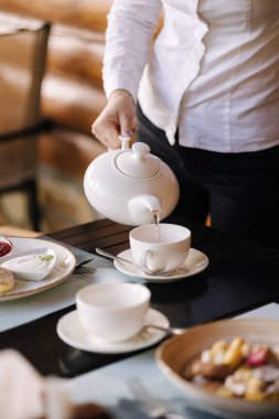 Garson misafirlere servis yapar ve fincana çay koyar. Restoranda kahvaltı. Yüksek kalite fotoğraf