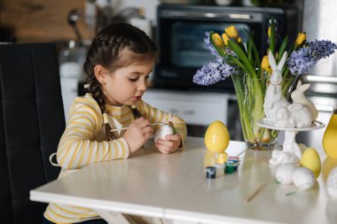 Küçük bir kızın mutfağa yumurta boyaması. Bahar tatili. Evde paskalya süsü. Yüksek kalite fotoğraf