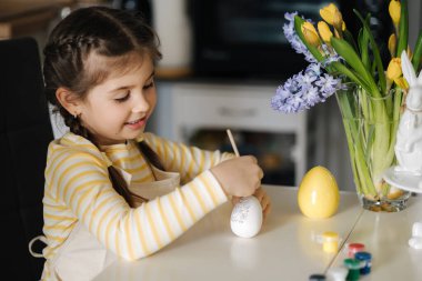 Küçük bir kızın mutfağa yumurta boyaması. Bahar tatili. Evde paskalya süsü. Yüksek kalite fotoğraf