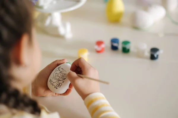 First person view of little girl painting easter egg. High quality photo