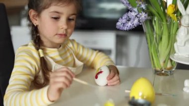 Mutfağa paskalya yumurtası boyayan mutlu küçük kız. Sevimli gülümseyen kız bahar tatilinde iyi eğlenceler. Yüksek kalite 4k görüntü