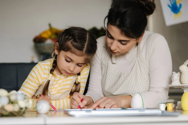 妈妈和她可爱的小女孩坐在厨房的桌子边 用铅笔给照片涂色 高质量的照片 — 图库照片