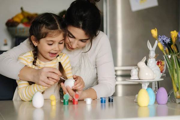 Portrait of mom and daughter painting easter eggs on kitchen. Spring holidays mood. Family. High quality photo
